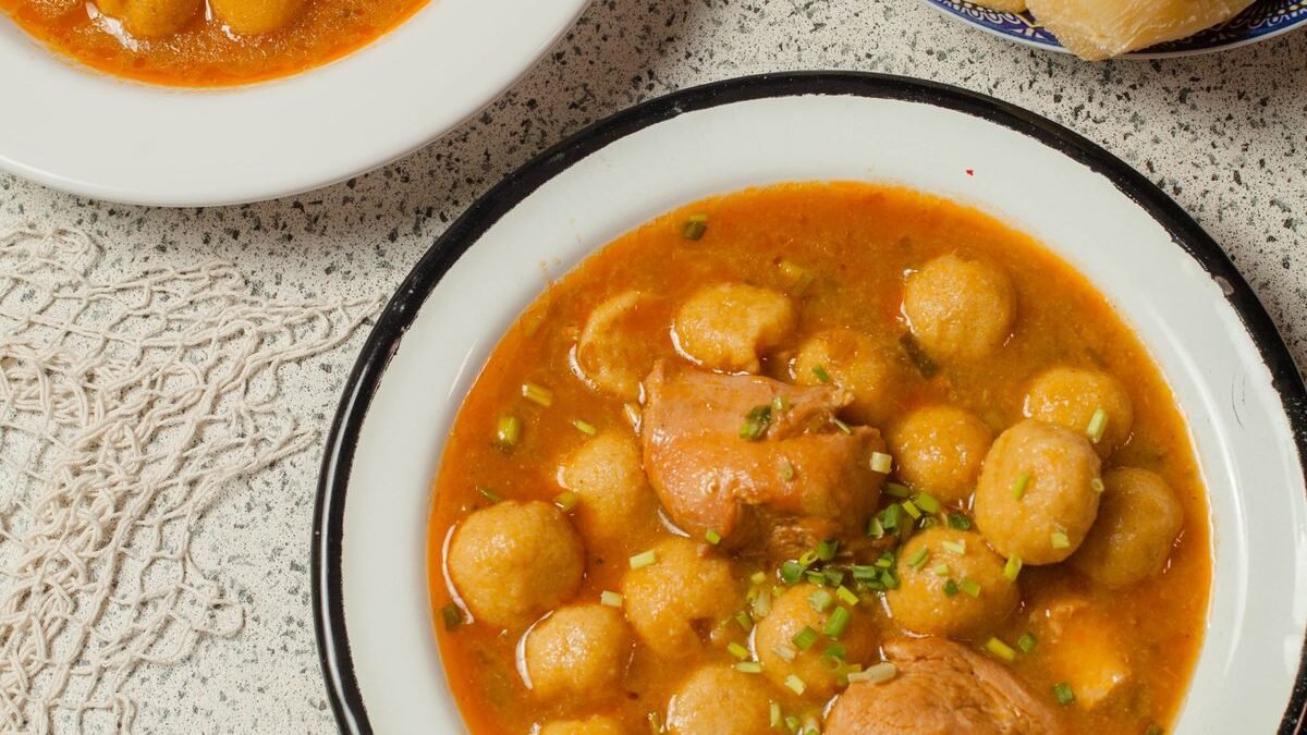 Bowl of chicken and dumplings in a rich broth garnished with fresh herbs