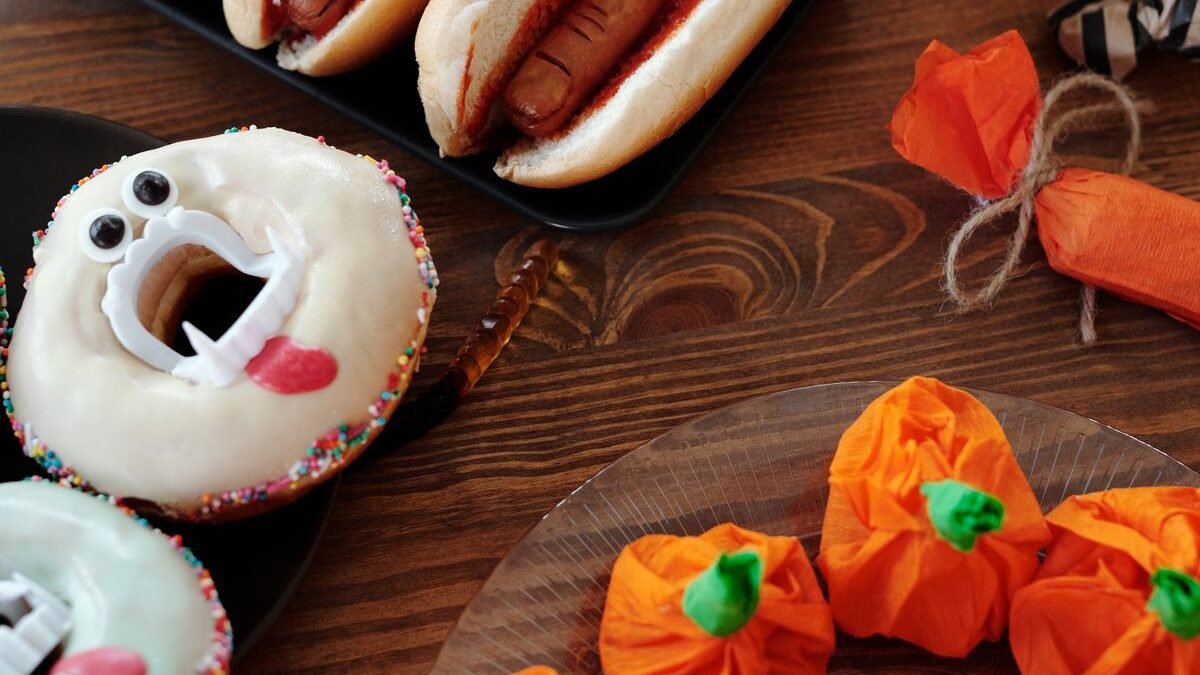 Halloween sugar cookies shaped like bats and a pumpkin with black and orange icing