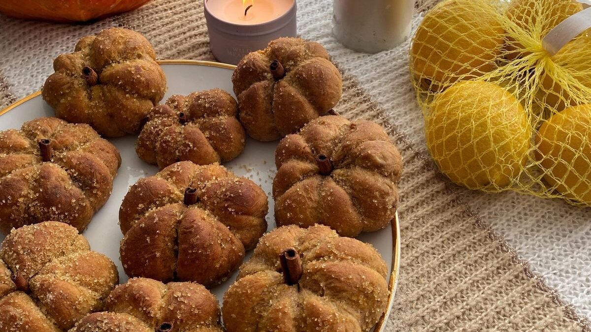 Plate of golden dinner rolls shaped like little pumpkins with cinnamon-stick stems
