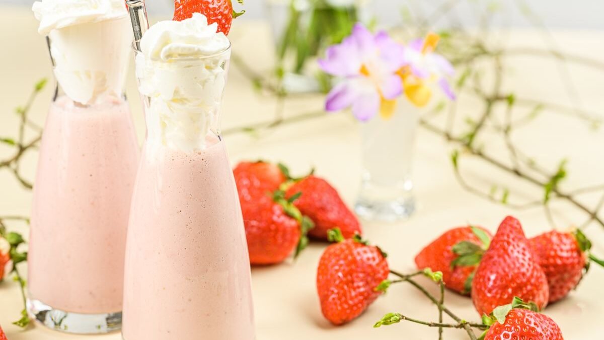 Pink strawberry cold foam drink topped with cream and fresh strawberries